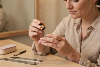 Femme appliquant de l'huile nourrissante sur des ongles épais et durs lors d'une routine de soin des ongles à domicile